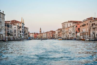 Canal in city against clear sky