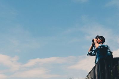 Low angle view of person photographing against sky