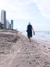 Man on beach against sky in city