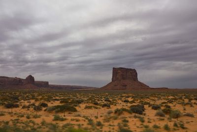 Rock formations on landscape against cloudy sky