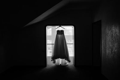 Bridal gown hanging on door in dark room