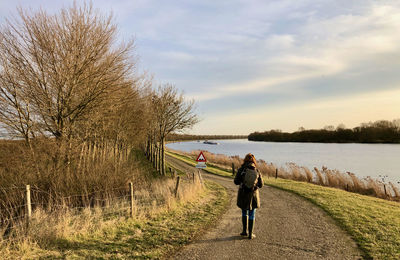 Rear view of people walking on shore against sky
