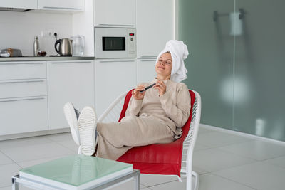 Home chores. home routines. funny young housewife with bathtowel on her head sitting in the chair