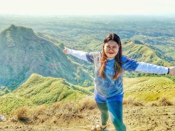Young woman with arms outstretched standing on landscape