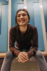 Low angle view of happy female athlete sitting in locker room