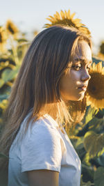 Side view of girl standing on sunflower field