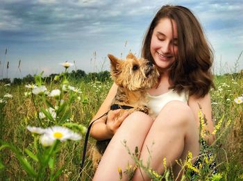 Young woman with dog on flower in field