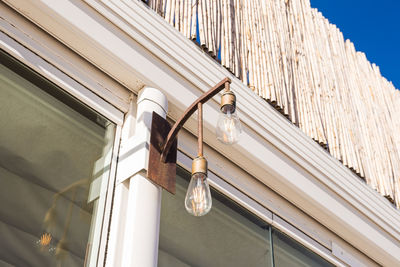 Low angle view of illuminated light hanging on ceiling of building