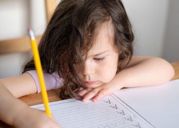 Young pretty is girl tracing letters in a book