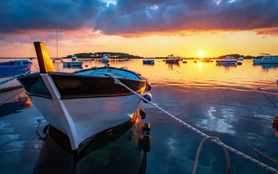 Boats moored in sea against sky during sunset