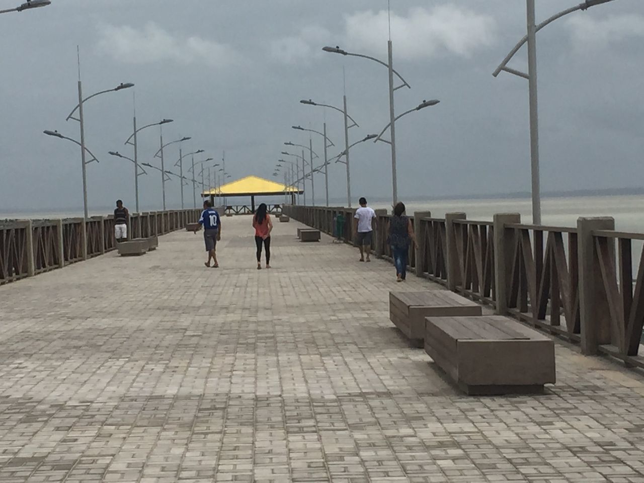 PEOPLE ON FOOTPATH BY SEA DURING RAIN