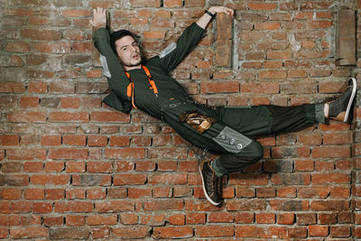 Portrait of man climbing on brick wall