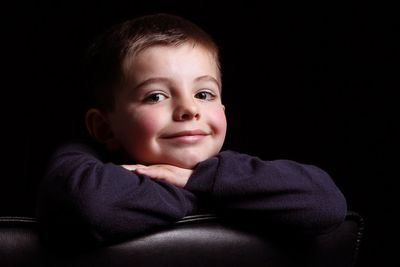 Portrait of cute baby boy against black background