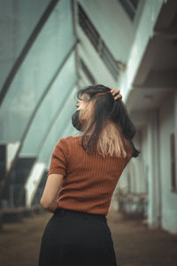 Side view of young woman standing against wall