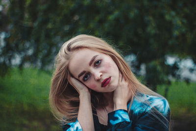 Portrait of beautiful young woman against trees