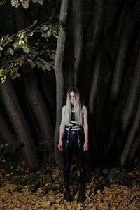 Young woman standing against trees in forest