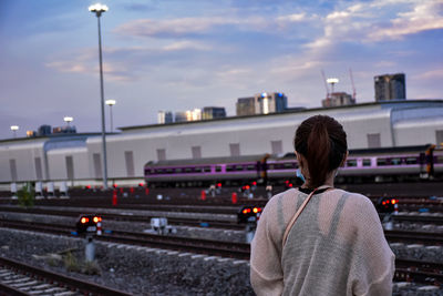 Rear view of man standing on train against sky