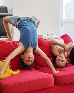 Siblings kids having fun playing going upside down on the sofa
