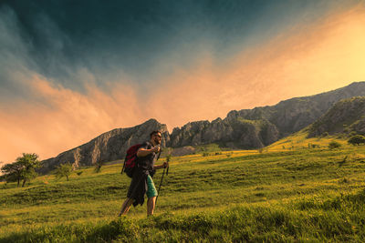 Low angle view of hiker walking on mountain against sky