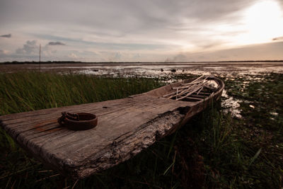 Wooden log on field against sky during sunset