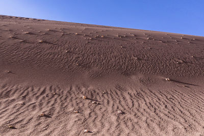 Sand dunes in desert against clear blue sky