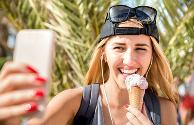 Portrait of smiling young woman using smart phone outdoors