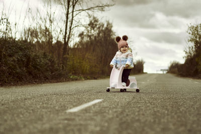 A 1 year old baby girl is with a pink motorcycle outside