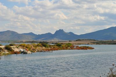 Scenic view of coastline against cloudy sky