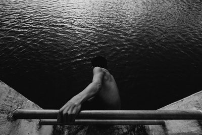 High angle view of shirtless man on ladder by sea