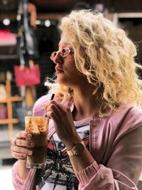 Close-up of young woman holding drink in restaurant