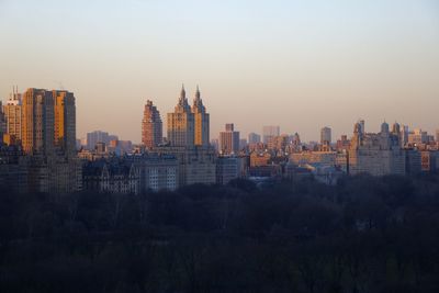 Buildings in city against clear sky during sunset