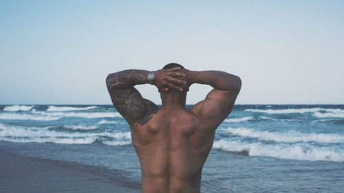 Low angle view of shirtless man at beach against sky