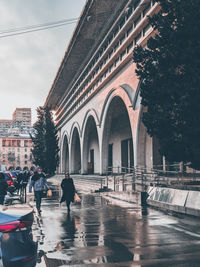 People walking on wet street in city during rainy season