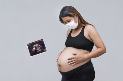 Young woman looking away while standing against white background