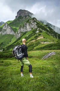 Rear view of man looking at mountains against sky