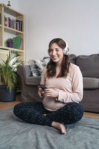 Portrait of smiling woman sitting on sofa at home