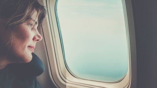 Side view of young woman looking through window