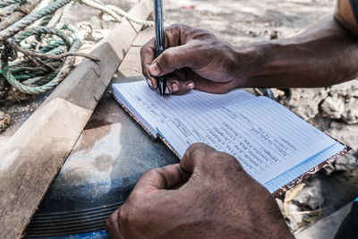 Cropped hands of man writing in diary