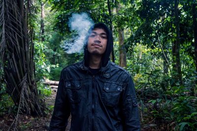 Portrait of man exhaling smoke in forest