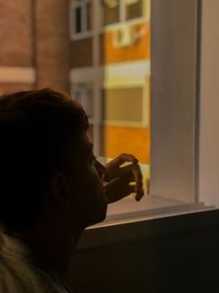 Man smoking against window at home