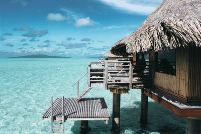 Stilt house at beach against sky