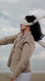 Side view of woman with blindfold standing on beach