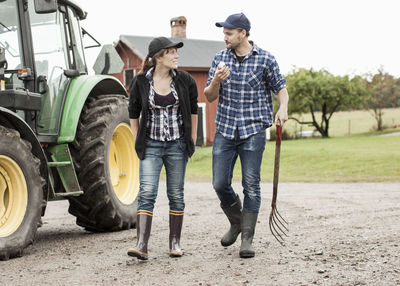 Full length of farming couple walking by tractor