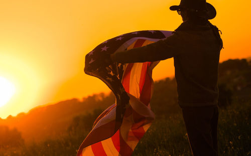 Man holding american flag during sunset