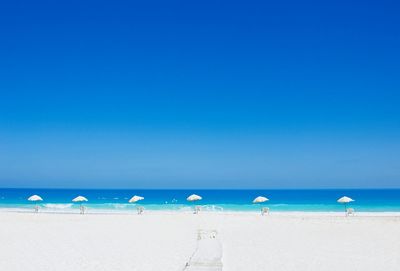 Parasols on beach against clear blue sky