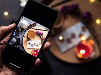 Close-up of hand holding smart phone on table