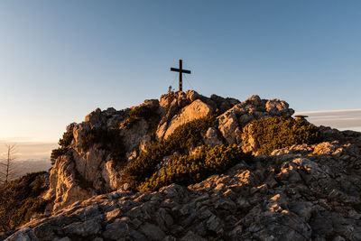 Cross on rock formation against sky