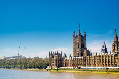 View of building by river against blue sky