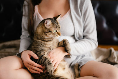 Midsection of woman with cat at home