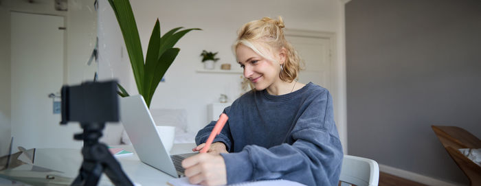 Young woman using laptop while sitting on sofa at home